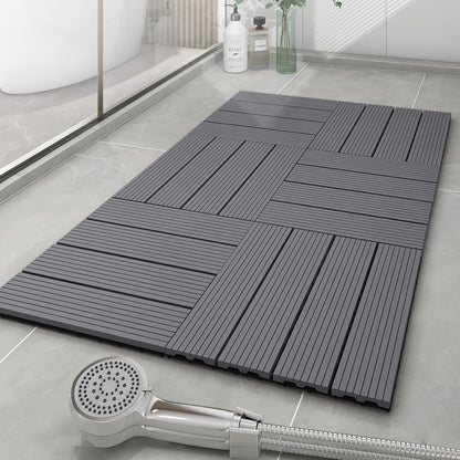 Gray interlocking shower tiles on a bathroom floor with a handheld shower head.