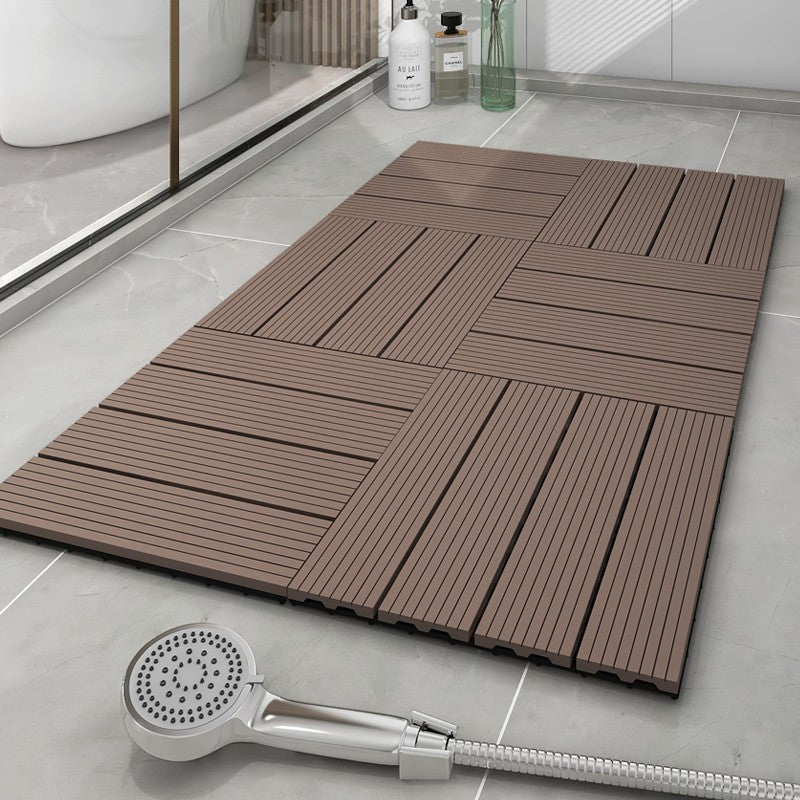 Brown interlocking shower mat on a tiled bathroom floor with a handheld shower head.